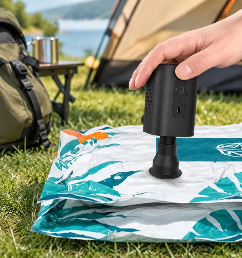 Hand holding the pump above a vacuum storage bag with nozzle attached