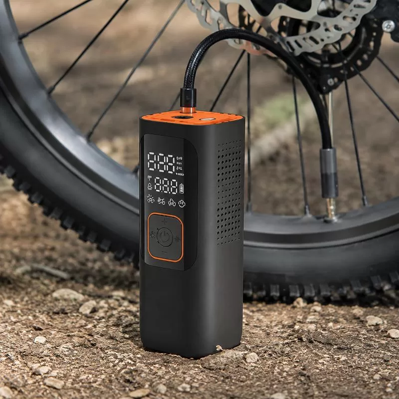 Front three-quarter view of a compact black and orange electric tire inflator with digital display