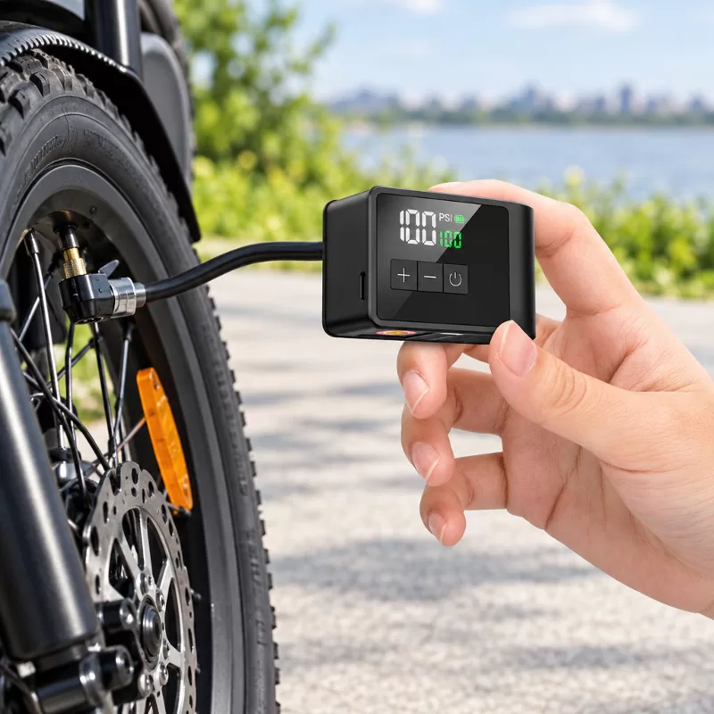Type-C Fast Charging on Compact Electric Bike Pump Close-up of a compact black electric bicycle tire pump resting on a dark surface with a Type-C charging cable plugged into the side port